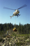 Helicopter holds a net full of fire fighting gear above the ground by Douglas Beck