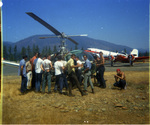 Men standing by helicopter by Douglas Beck