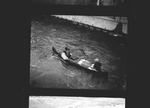 Two men in a canoe paddle through a channel in the partially constructed Grand Coulee Dam by Hubert Blonk