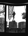 Worker attaches four-yard bucket for concrete to crane by Hubert Blonk