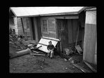 Boy sitting in a littered yard by Hubert Blonk