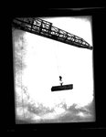 Worker standing on beams suspended by a crane by Hubert Blonk