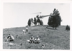 Helicopter above a hillside where people are gathered by Peyton Moncure