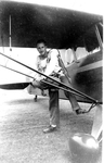 Chet Derry leaning on wing strut by unknown