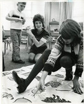 Woman points at object on mat with teacher and student watching by Eastern Washington University