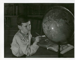 Globe and atlas observed by a student in the library by Eastern Washington College of Education