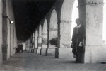 Woman standing next to arches of the San Miguel Mission by Robert Gillette