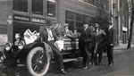 Group of men sitting in and gathered around one of the official Mitchell Six automobiles used during the National Parks Highway Association tour by Frank W. Guilbert