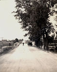 Touring car parked on dirt road in front of a bridge by Frank W. Guilbert